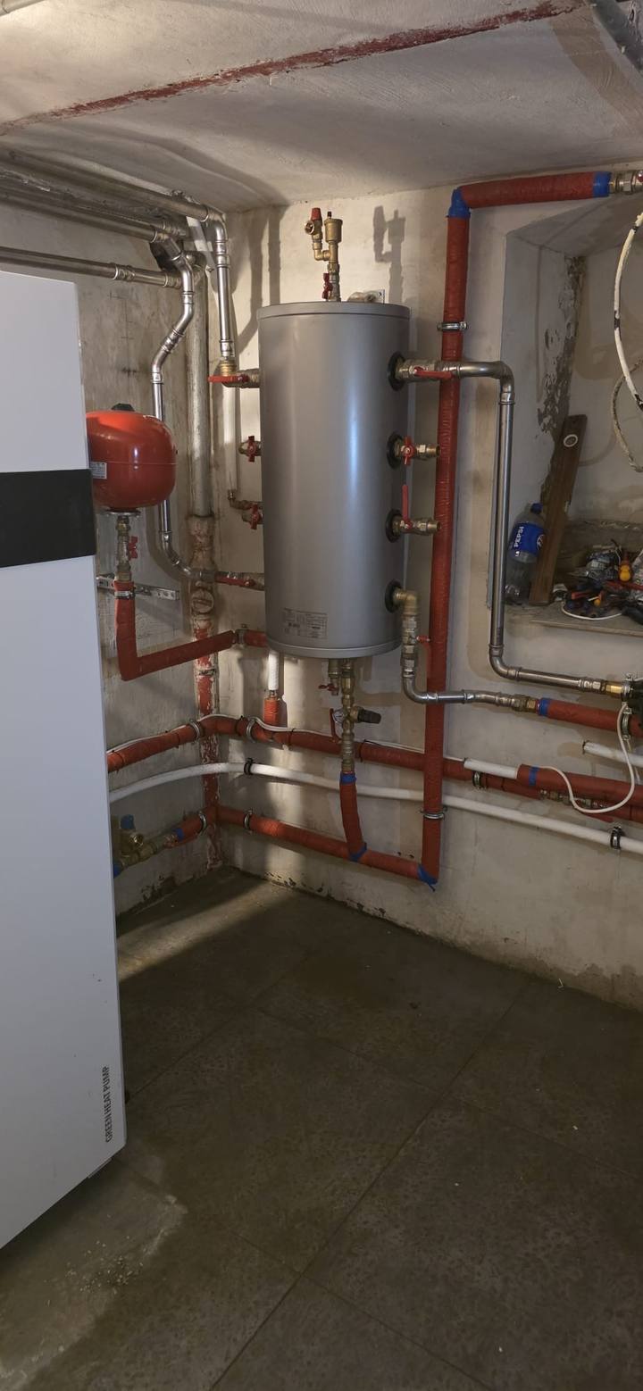 Tuberías aisladas y bien alineadas junto a un depósito en una sala técnica