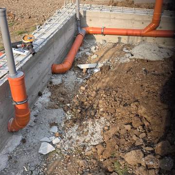 Tubería de saneamiento y bajantes junto a un muro de hormigón